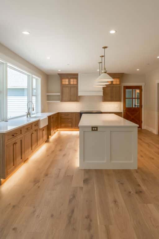 Custom maple wood shaker style kitchen cabinets with cabinet lighting and marble countertops
