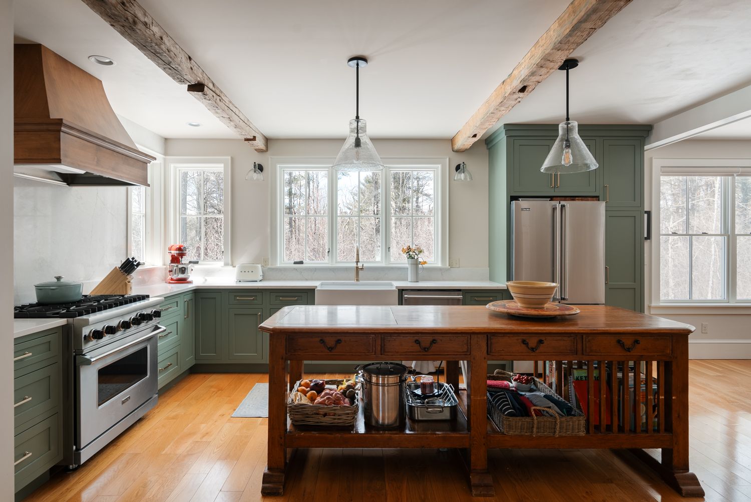 Maine kitchen with warm honey wide-plank hardwood flooring and sage green shaker cabinets