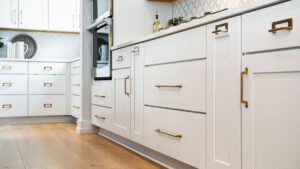 Freshly painted white shaker kitchen cabinets with brass hardware and a hardwood floor