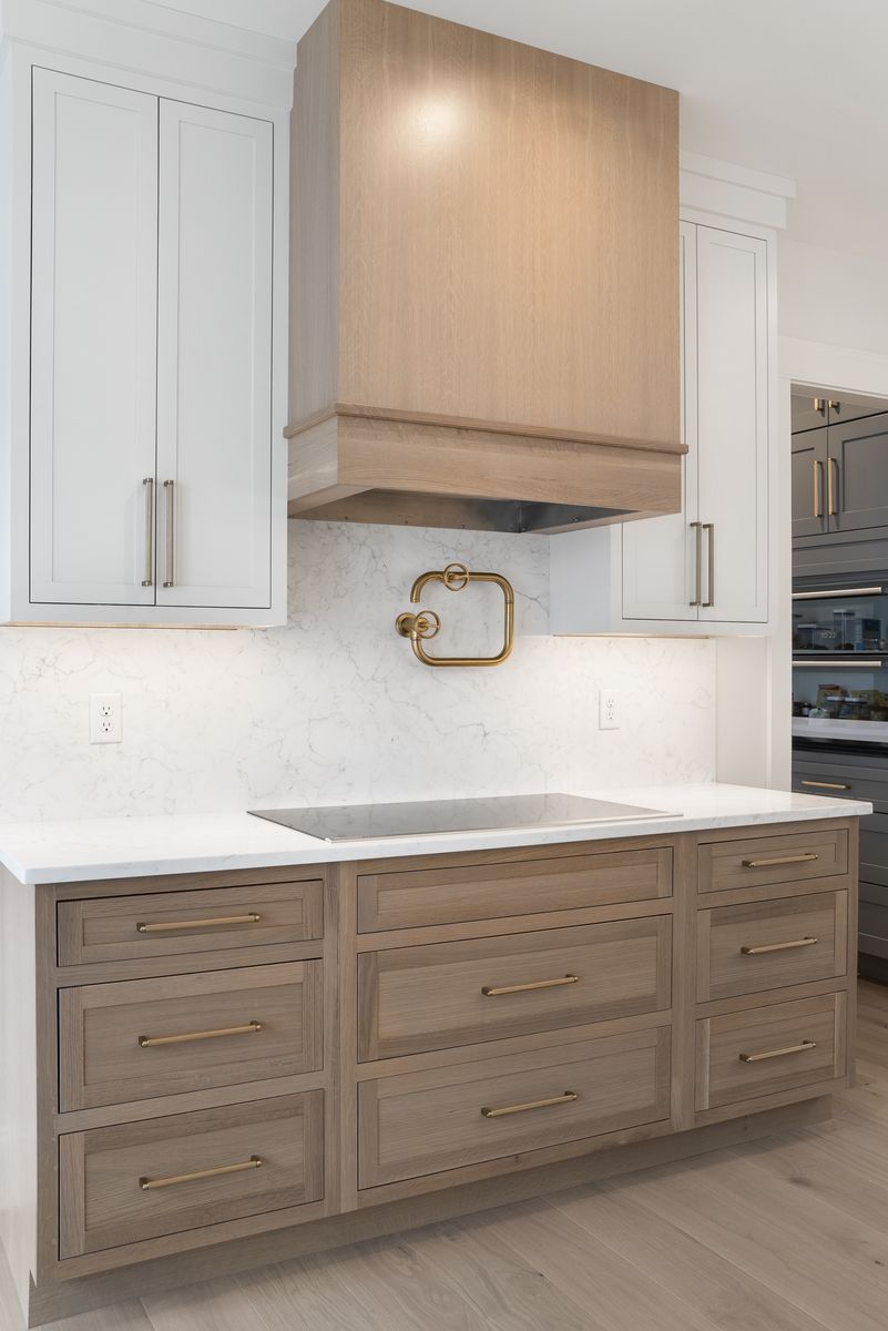 Detail of a custom white oak range hood and brass hardware in a Scarborough, Maine kitchen