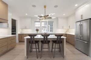 Custom white oak kitchen island with quartz countertop and brass lighting in a Scarborough, Maine home