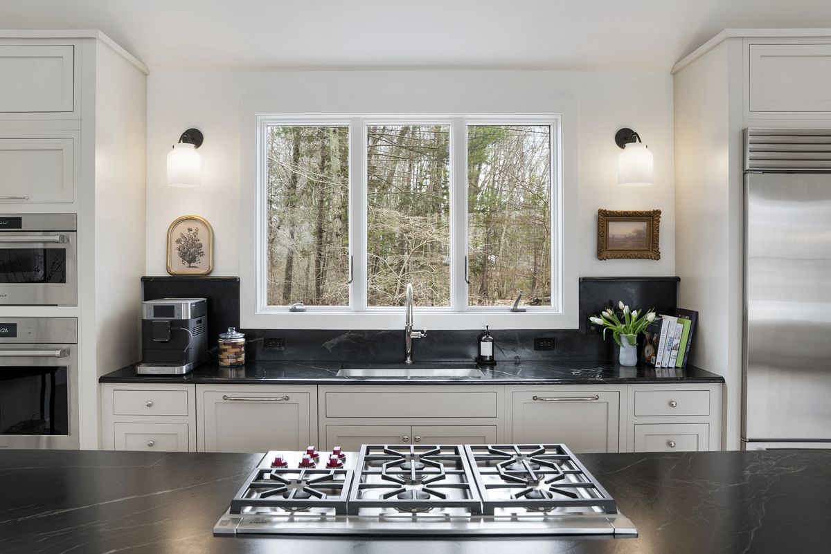 Professional gas cooktop set into a honed black island countertop in a Yarmouth, Maine kitchen