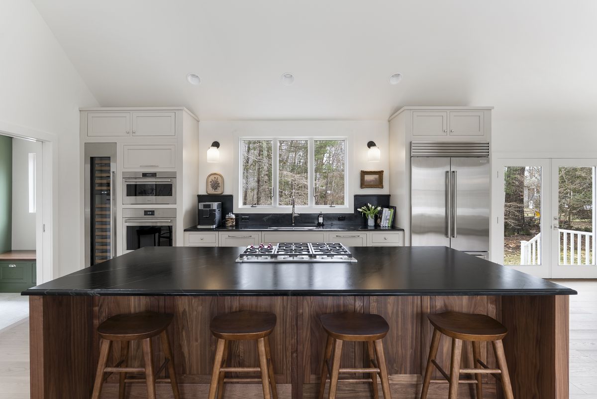 Walnut kitchen island with honed black countertop and counter stools in a Yarmouth, Maine home
